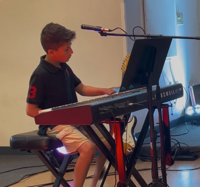 Student playing guitar on stage during the showcase